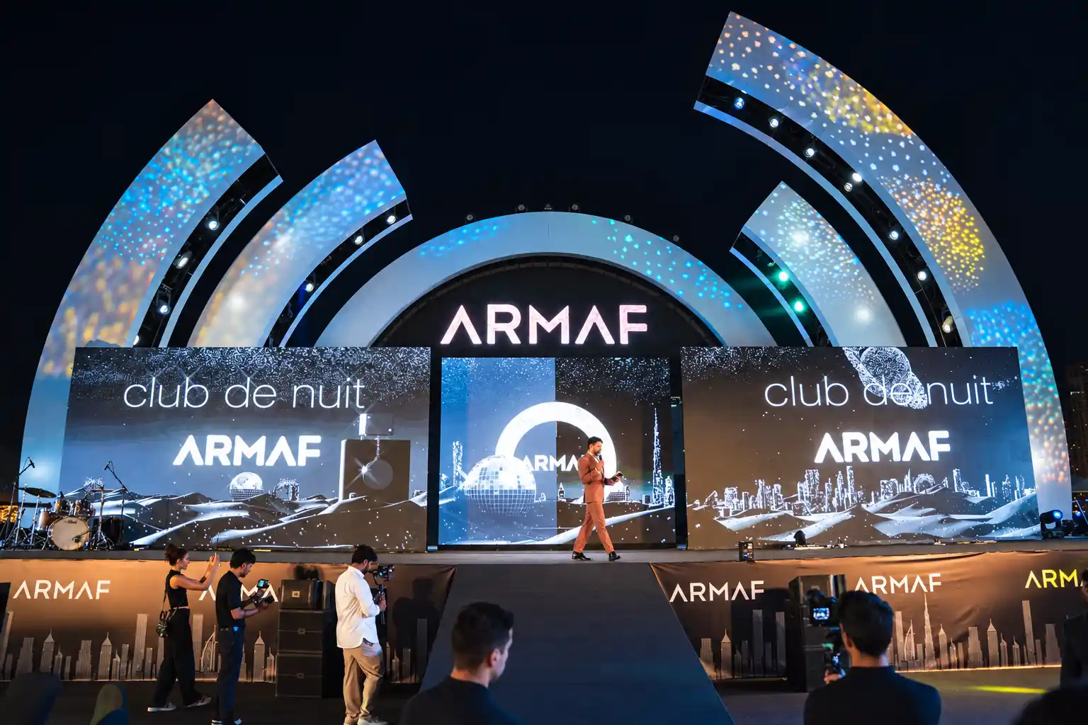Darryl Rees hosting the ARMAF Club de Nuit perfume launch on a large illuminated stage in Dubai, surrounded by branded LED screens.