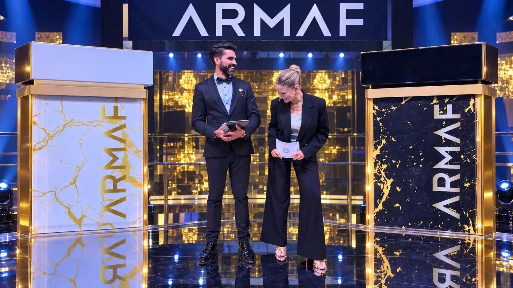 Darryl Rees and Shona a female presenter hosting the ARMAF perfume launch in Dubai, standing between branded displays beneath the ARMAF logo.