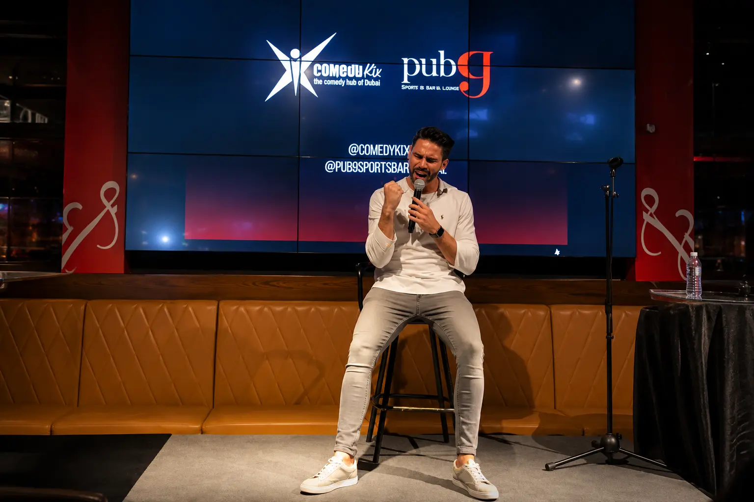 Stand-up comedian delivering engaging corporate entertainment on stage at a Dubai comedy venue.