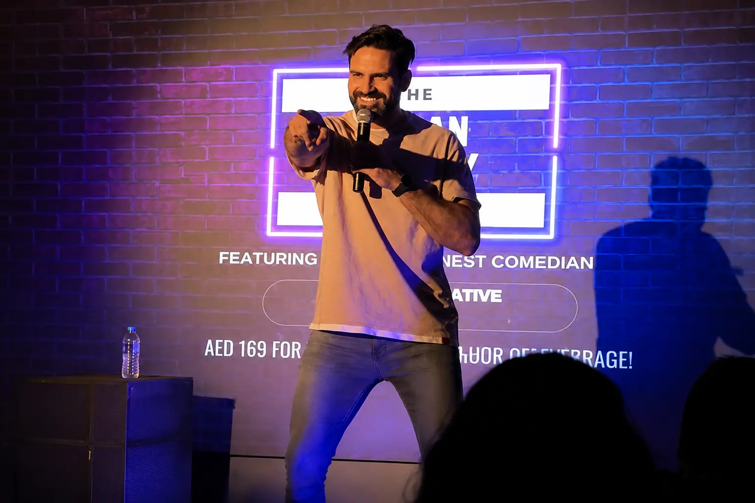Professional comedian delivering an interactive stand-up performance for a live audience at a Dubai event venue.