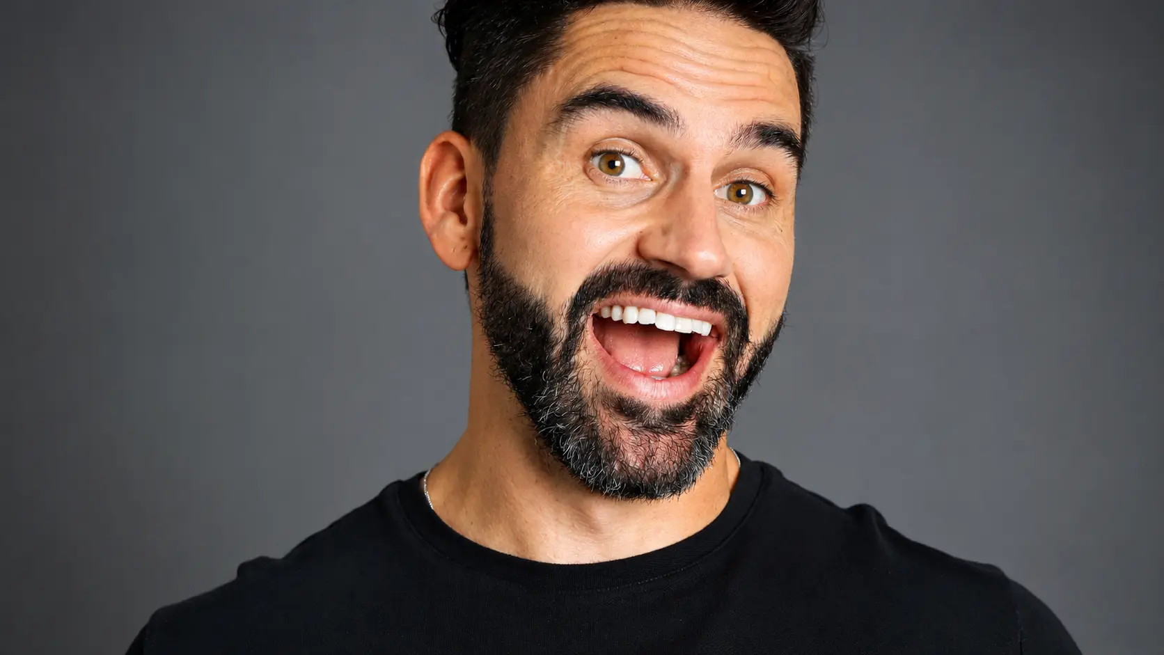 Professional headshot of a corporate comedian with an expressive and energetic smile, showcasing the personality and charisma essential for business event entertainment.