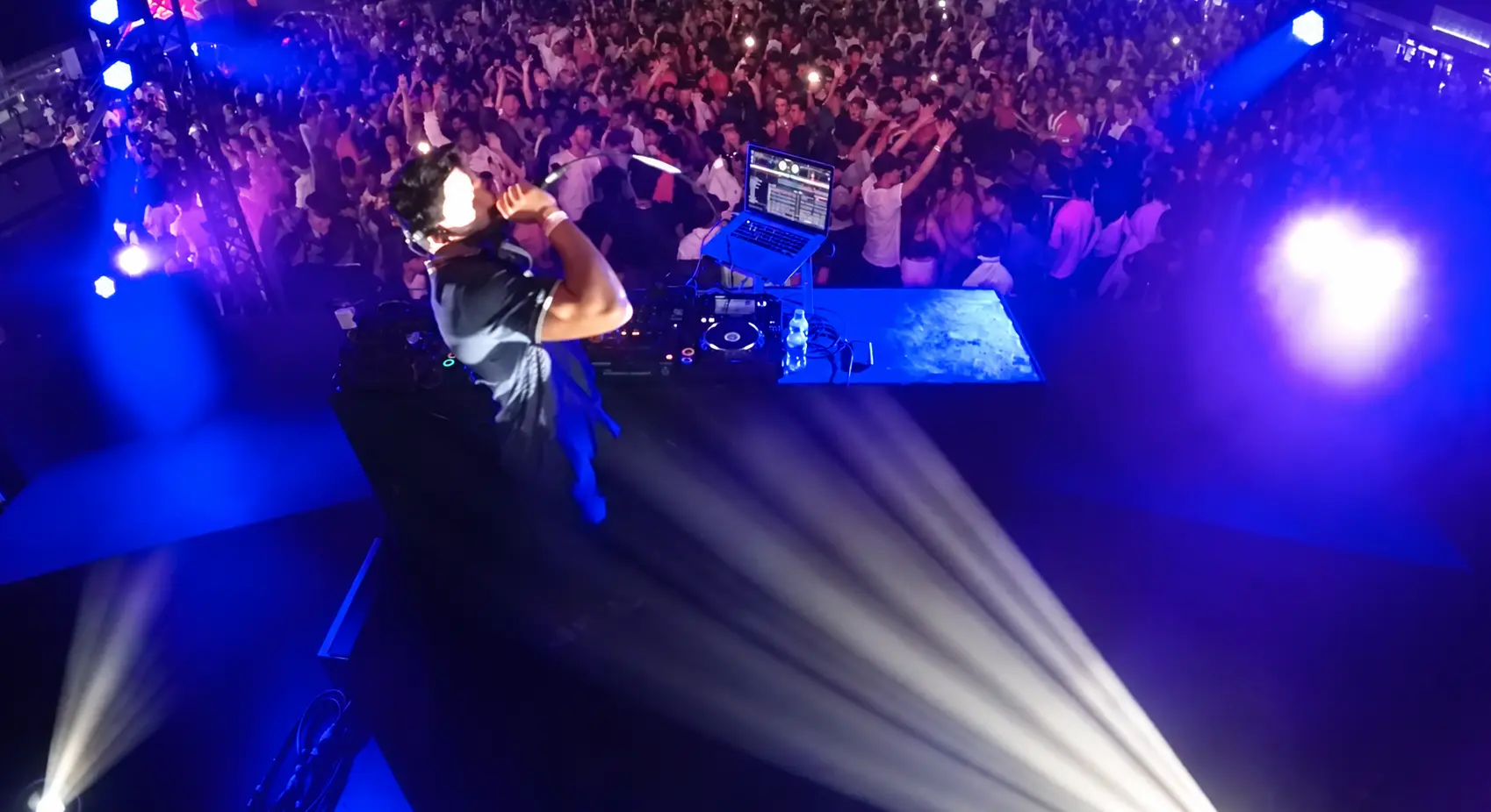 Darryl Rees DJing at du Arena in Abu Dhabi, with a lively crowd raising their hands under blue and purple stage lighting.